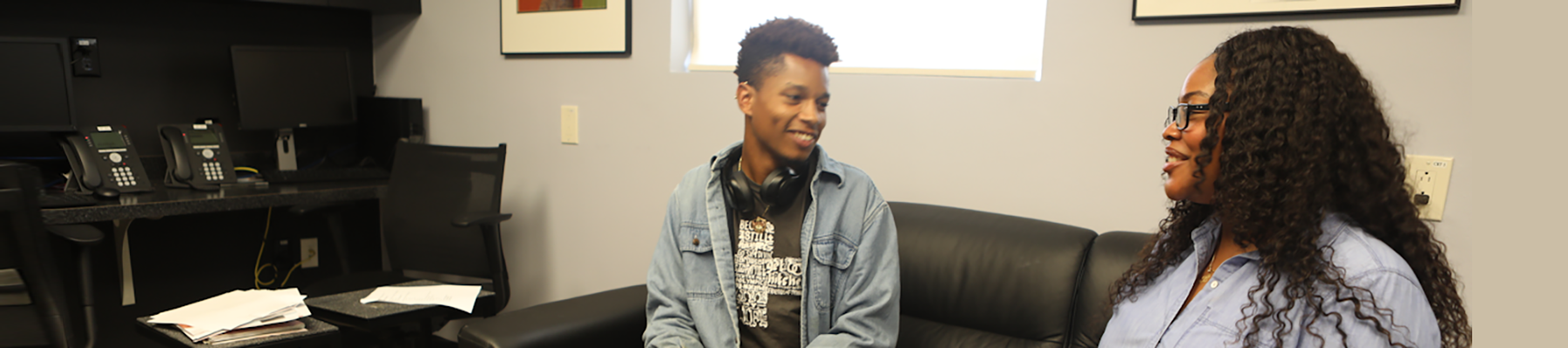 case manager with patient Young black man sitting on a couch in an office talking to a black woman